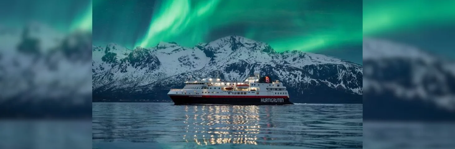 Hurtigruten vessel sailing in Norway with the Northern Lights in the background
