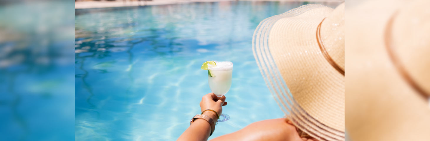 A holidaymaker stood at the edge of the pool holding a cocktail.