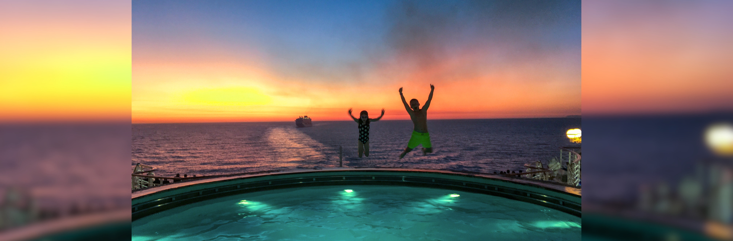 Two children jumping into a swimming pool on the stern of a cruise ship.