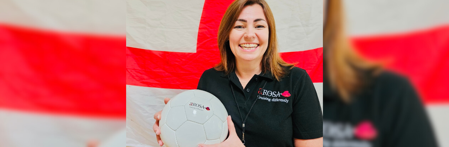 Michelle Daniels, sales director at A-ROSA River Cruises, holding a football in front of a St. George's Flag.