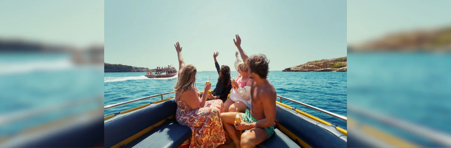 A group of friends waving from the rear of a boat.