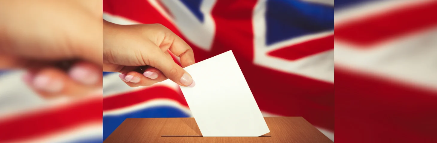A hand casting a vote into a ballot box, with the Union Flag in the background.
