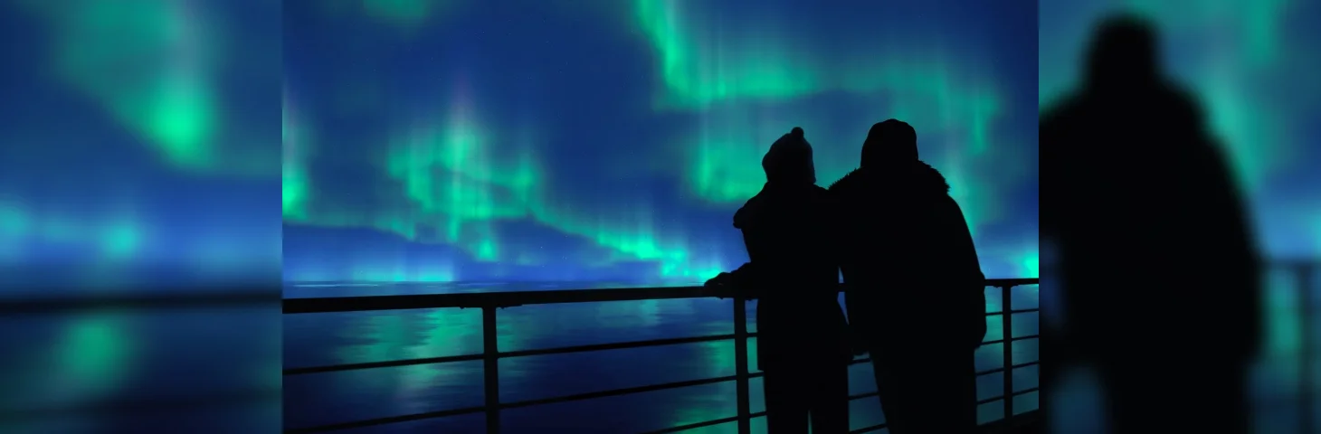 Two people watching the Northern Lights from the deck of a cruise ship.
