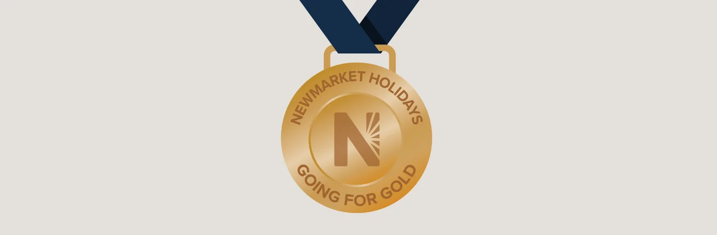 A gold medal with the Newmarket Holidays logo embossed on it.