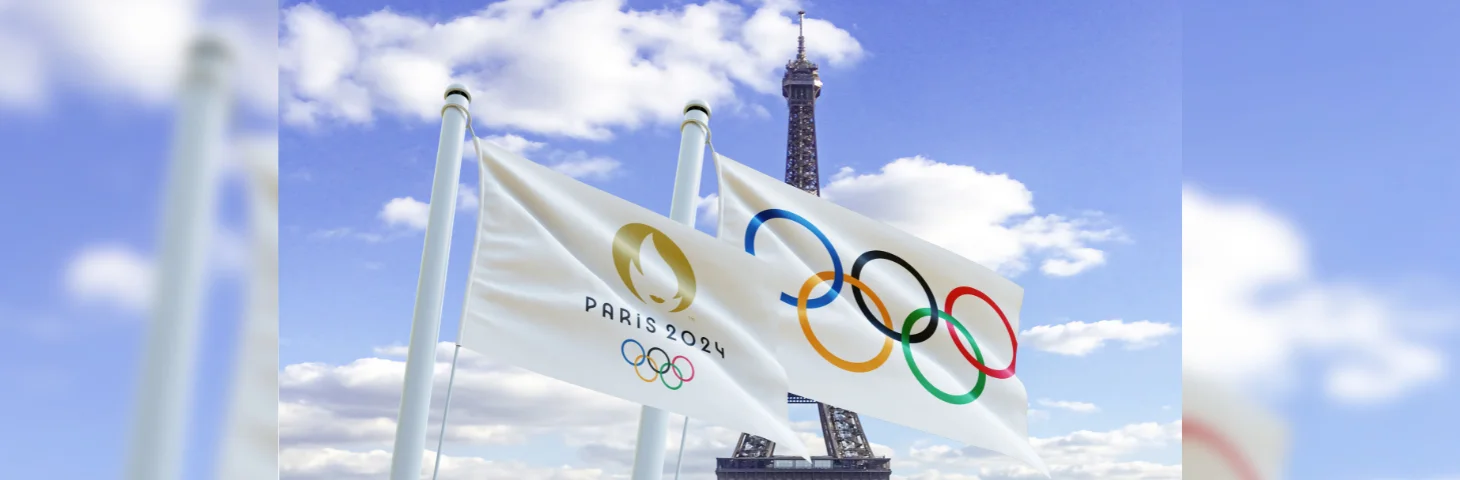 Two Paris 2024 Olympic Games flags waving in front of the Eiffel Tower.