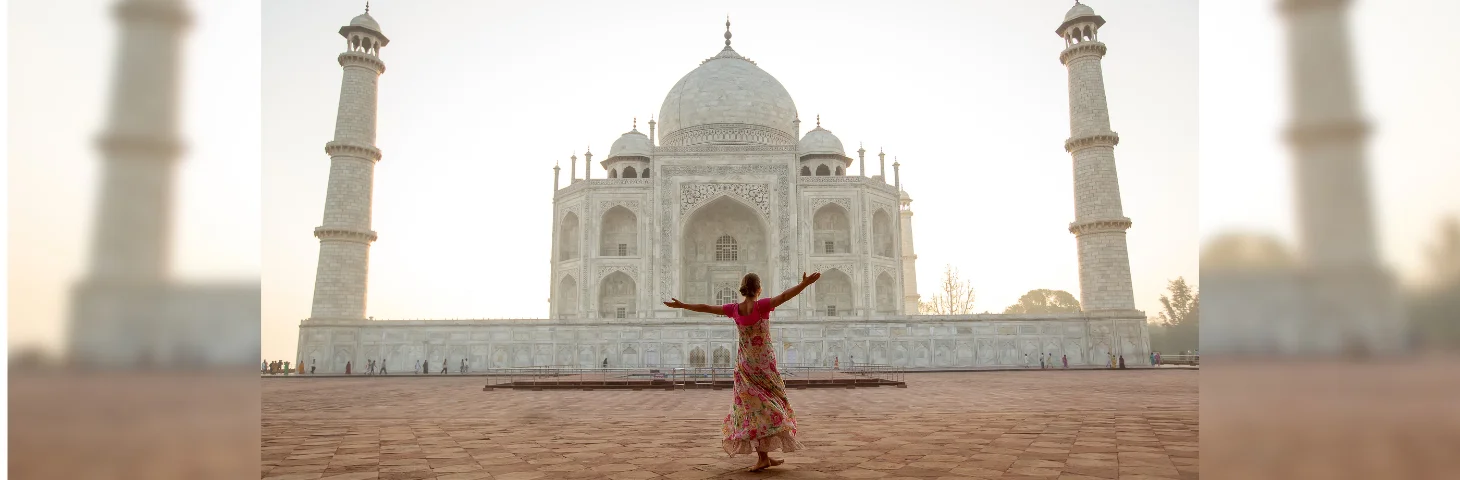 A person stood with their arms outstretched in front of the Taj Mahal in India.