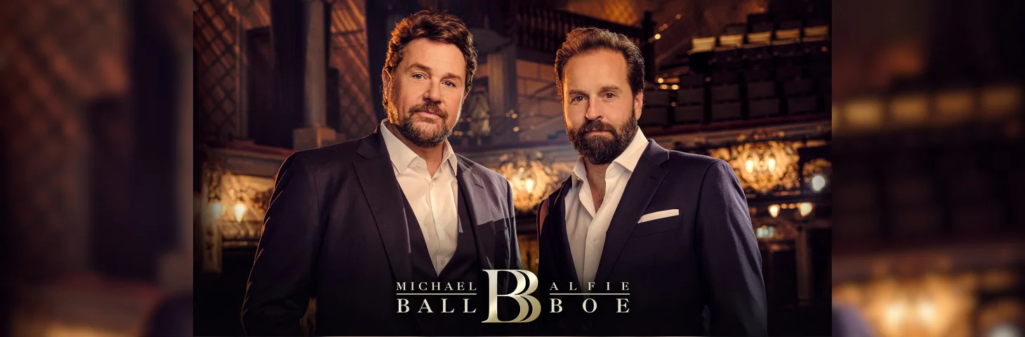 Michael Ball and Alfie Boe in an opera venue wearing three-piece suits.