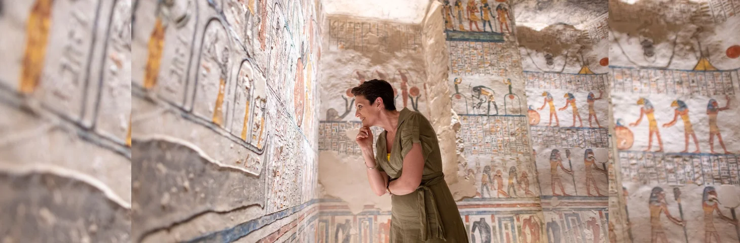 A traveller in a tomb in Egypt looking at hieroglyphics.