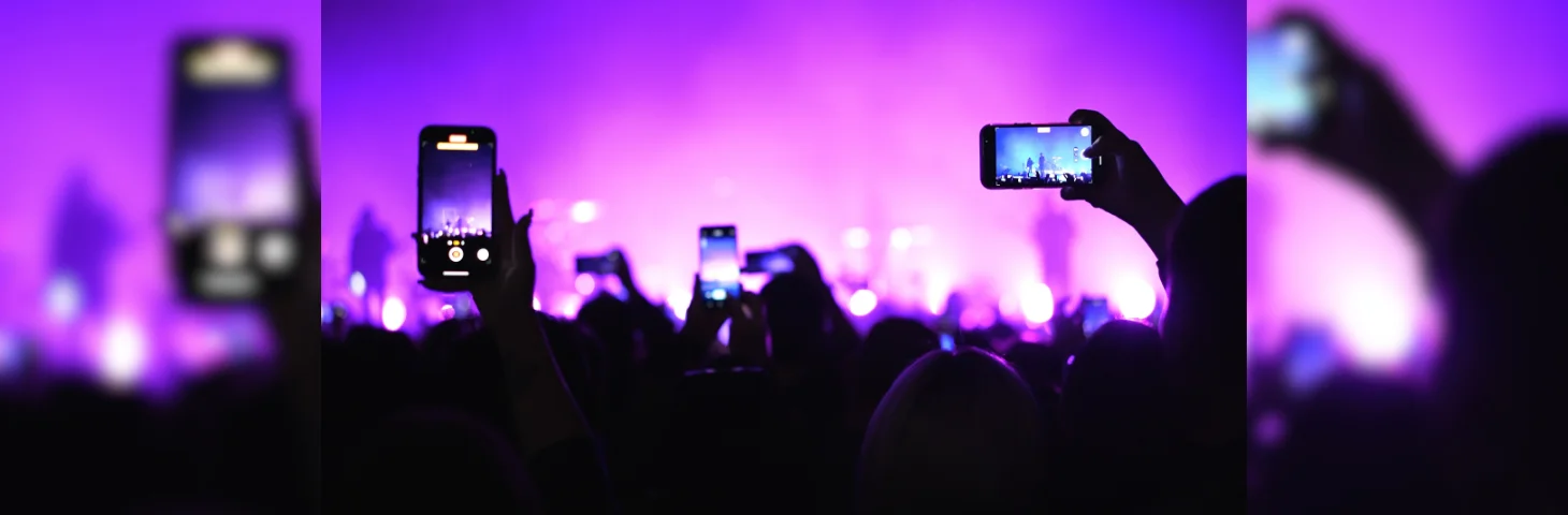 The crowd at a concert, with several members recording video on their phones.