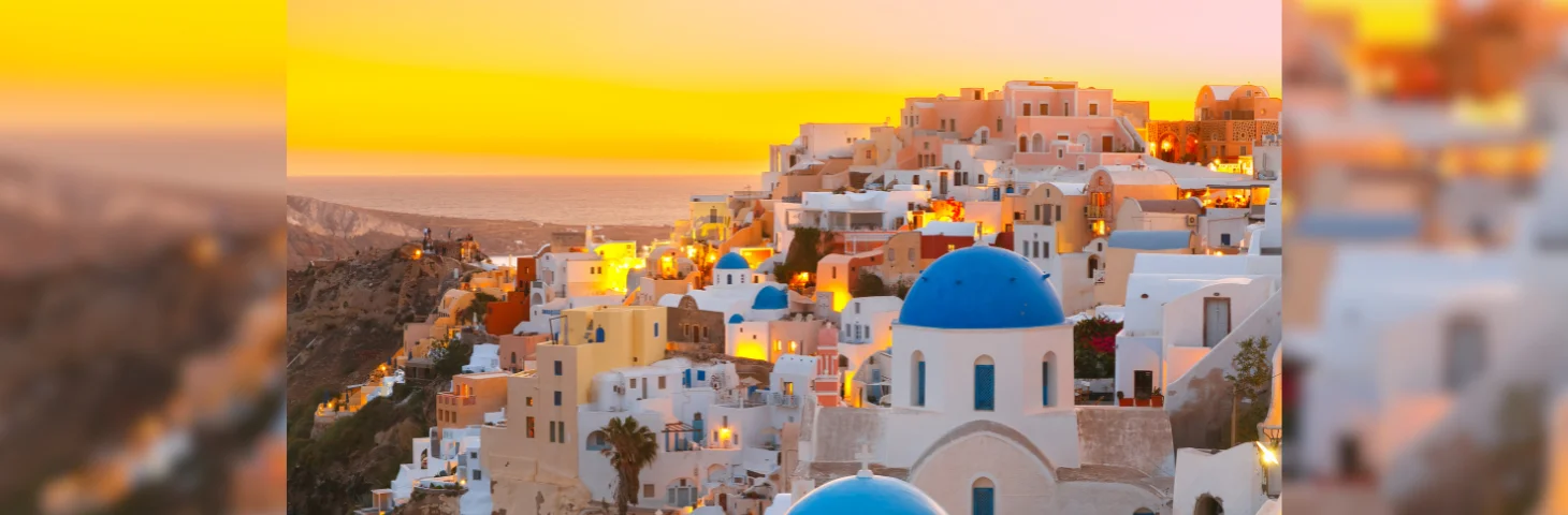 An aerial view of Oia, Santorini, Greece at sunset, with the sea in the distance.