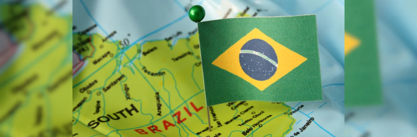 A Brazil flag on a pin placed into a map of Brazil.