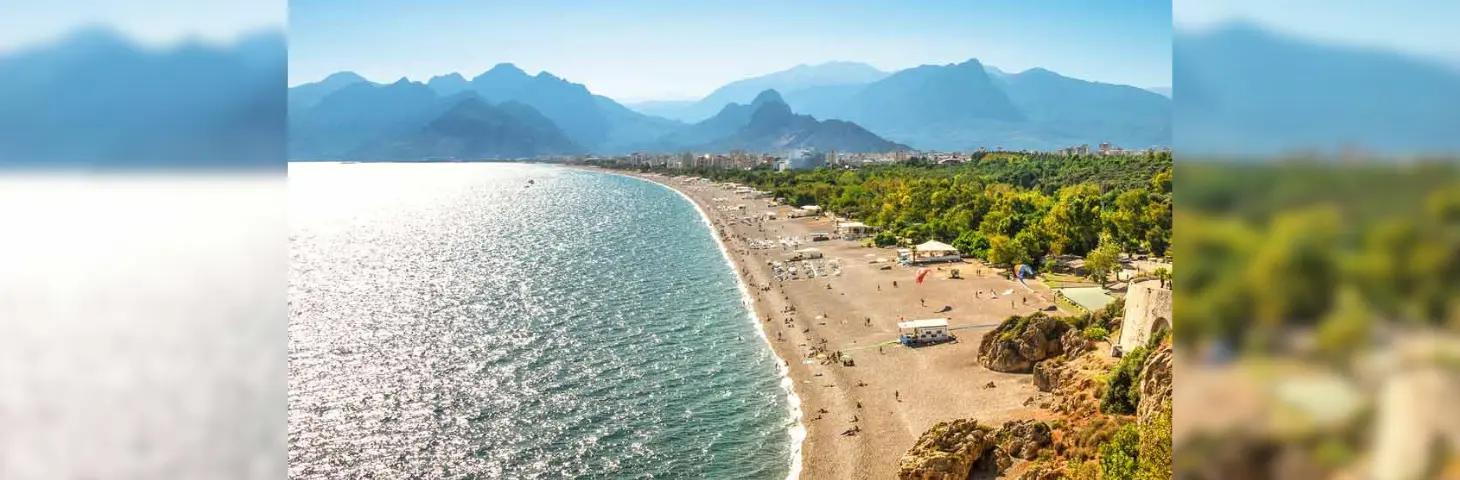 Image of a beach with mountains and foliage in the background