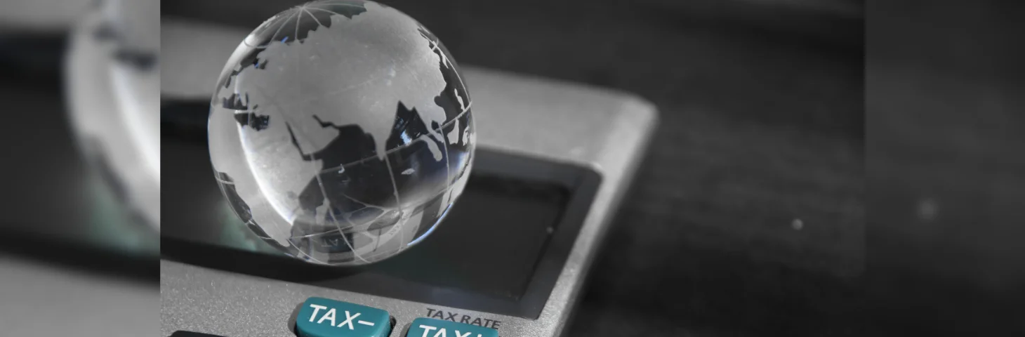 A glass sphere embossed with a world map laying on top of a calculator.