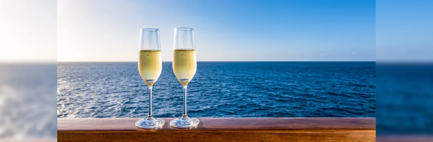 Two glasses of Champagne on the handrail of a cruise ship at sea.