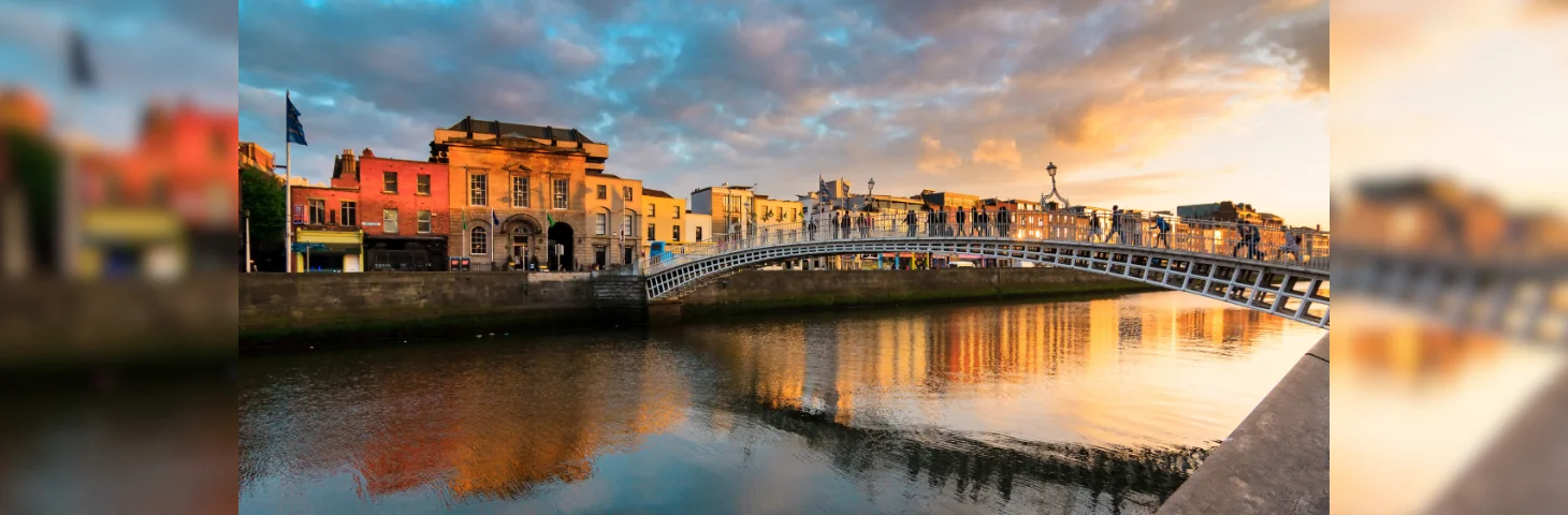 The Ha'penny Bridge in Dublin, Ireland at sunset from the bank of the River Liffey.