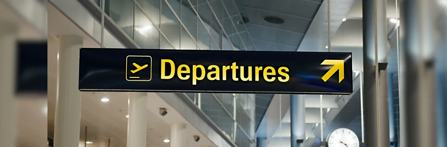 A sign pointing towards the Departures area at an airport.