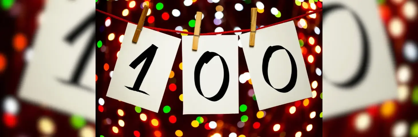100 sign pegged to a line with fairy lights in the background