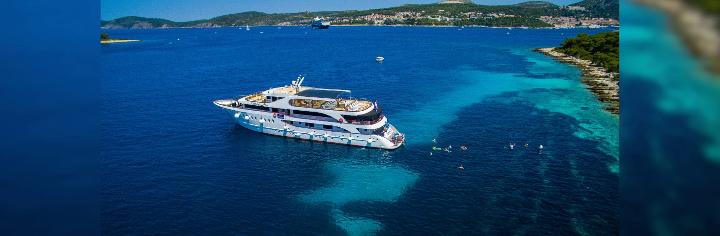 Romantic Star docked into the blue waters with guests splashing around behind it