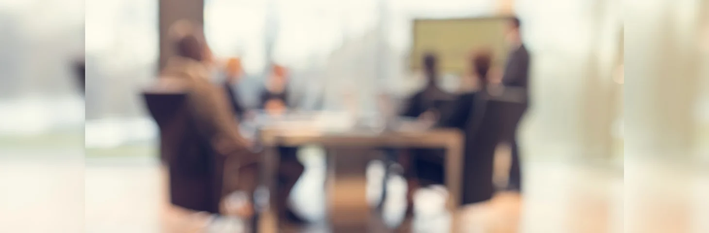 A blurred image of a boardroom meeting of an advisory panel.