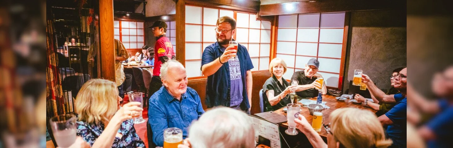 An InsideJapan tour manager raising a glass at dinner in a traditional Japanese restaurant.