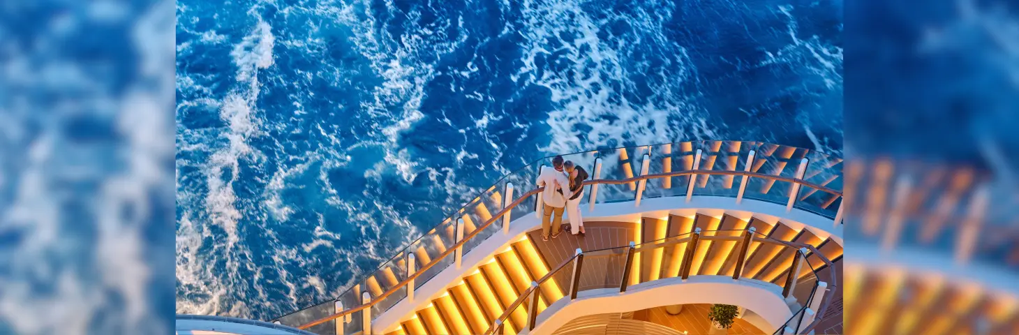 Couple huddled together on a lit stairway looking into the sea