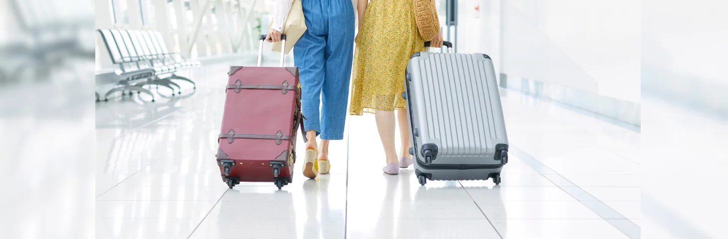 Two people wheeling their suitcases through an airport.