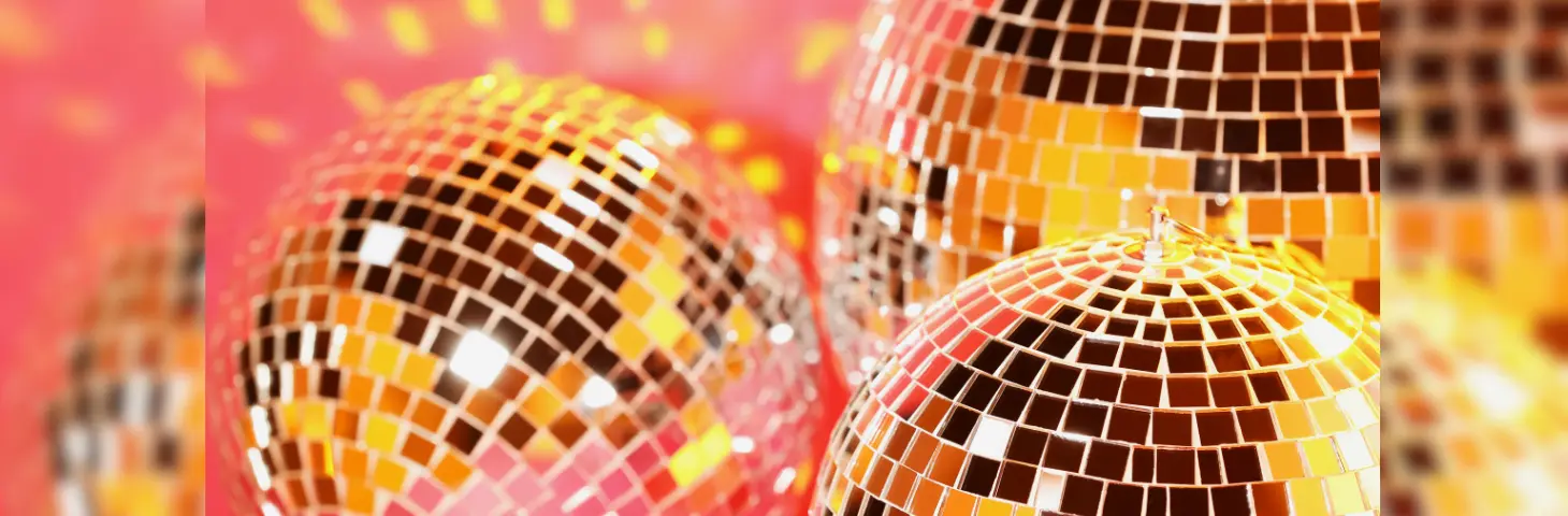 Three disco balls against a pink backdrop