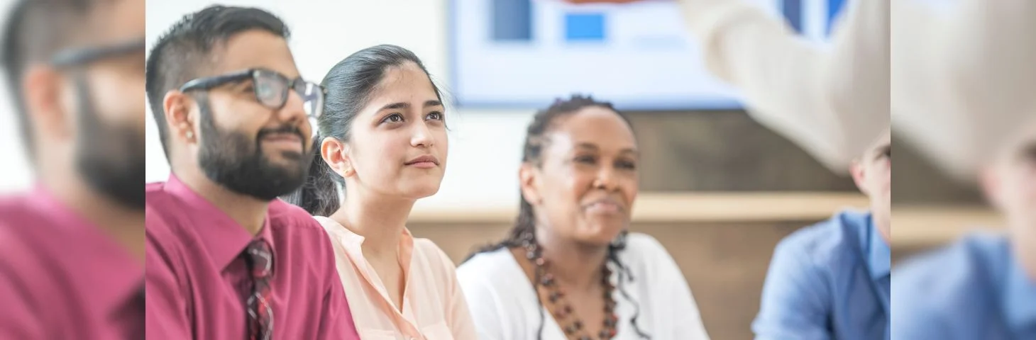 A group of businesspeople watching a pitch in a boardroom.