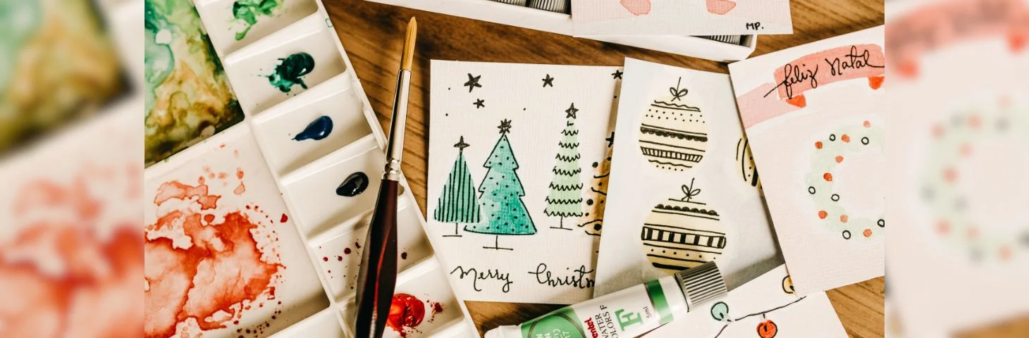 An array of handpainted Christmas cards on a craft table.