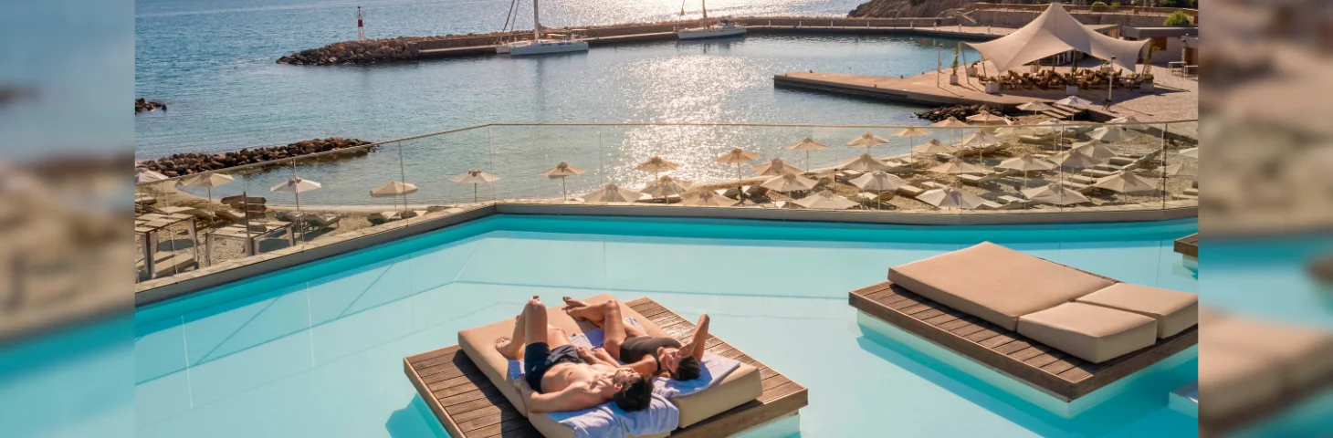 A couple sunbathing on the seafront area of ZEUS Eleva Mirabello Bay resort.