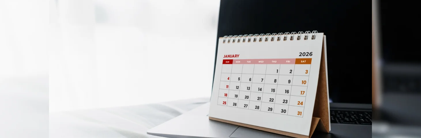 A 2026 calendar open on the January page, resting on top of an Apple Macbook laptop.