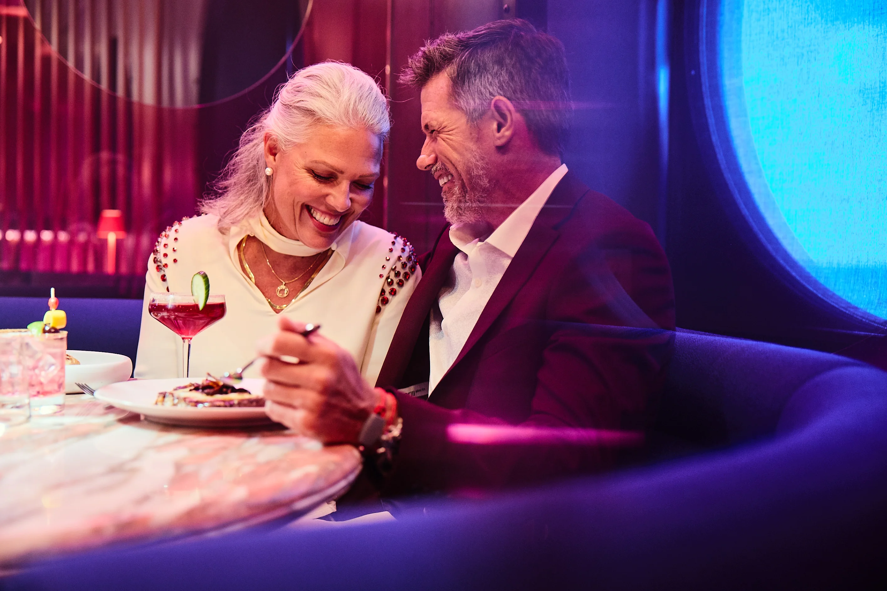 A couple drinking wine in the lounge aboard a Virgin Voyages ship