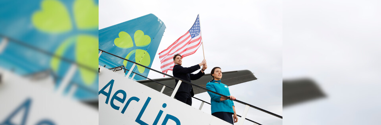 Aer Lingus staff, one of whom waves an American flag, stood on the staircase leading from an Airbus A330.
