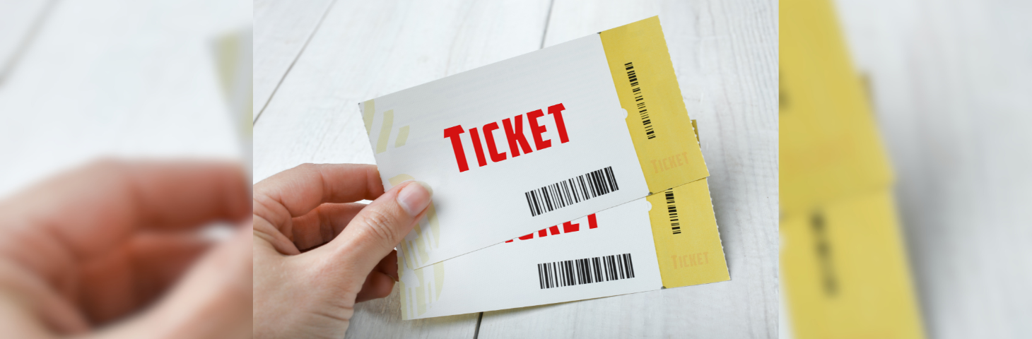 Stock image of a hand holding two generic event tickets.
