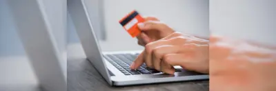 Someone making a payment card on a laptop, reading their card details. 