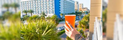 A tattooed person holding a pint glass on the balcony of the 3 Daughters Brewing Co. in Clearwater, Florida.