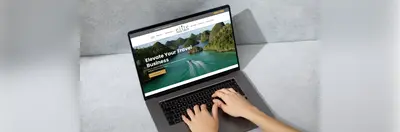 A pair of hands navigating the Elite Travel Group website on an Apple laptop.
