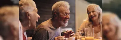 Three guests laughing around a dinner table on a Jules Verne Sociably Solo tour. 