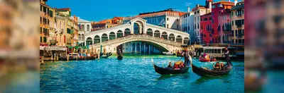 Gondolas sailing past Ponte di Rialto on Venice's Grand Canal.