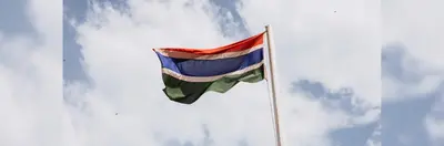 The flag of Gambia waving on a flagpole.
