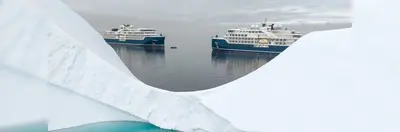 Two Swan Hellenic ships sailing past a glacier.