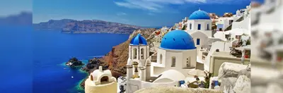 The iconic cliffside architecture and blue-domed churches of Santorini, Greece, overlooking the volcanic caldera and the Aegean Sea. 