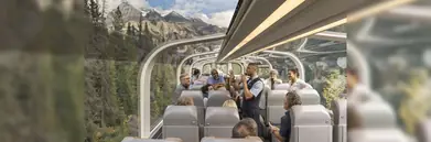 Inside the glass-top Rocky Mountaineer with the Rockies and forest in the background