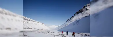 Three explorers walking through a snowy valley in Svalbard