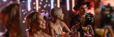 Two women and a man at a bar smiling