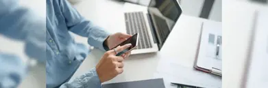 A man on his phone, next to a laptop