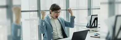 A man celebrating in front of his computer