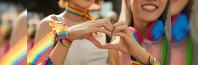 Two women making a heart at a pride parade 