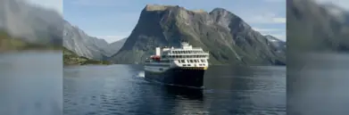 Havila ship sailing with mountain behind it
