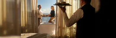 Waiter serving couple on balcony in Silversea suite